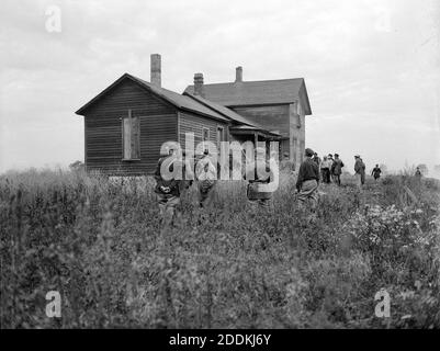 KEIN FILM, KEIN VIDEO, KEIN TV, KEIN DOKUMENTARFILM - Indiana Staatspolizei umgeben das Haus, wo zwei der Sträflinge waren angeblich aus der Michigan City Gefängnispause, ca. Oktober 1933. Am 26. September 1933 brachen 10 Strafgefangene unter der Führung von John 'Red' Hamilton aus dem Indiana State Prison in Michigan City, Ind., mit Waffen aus, die John Dillinger ihnen geschmuggelt hatte. In den kommenden Tagen nach der Gefängnispause berichtete die Chicago Tribune über '500 Wachtkräfte, Polizei und stellvertretende Sherriffs', die in den landwirtschaftlichen Bezirken in der Nähe von Michigan City nach den Verbrechern suchten. Dillinger, der sich in einer Gefängniszelle in Lima, Ohi, befand Stockfoto