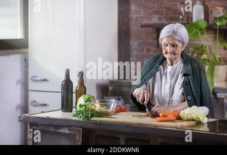 Ältere Frau hacken frisches Gemüse für Salat. Gesunde Essgewohnheiten. Stockfoto