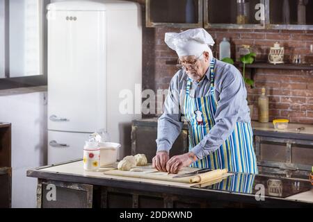 Senior Mann im Chefkoch hat Gebäck in der Küche zubereitet Zu Hause Stockfoto