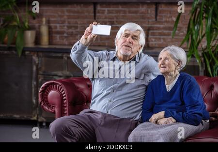 Senior Paar unter selfie mit Smart Phone beim Sitzen auf der Couch zu Hause Stockfoto
