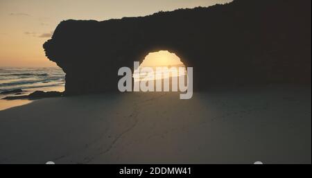 Felswand, riesiges Loch in der Sonne Silhouette Luftaufnahme. Sand Ocean Coast Touristenattraktion am Bawana Beach, Sumba Island, Indonesien. Sommer Morgen Attraktion tropisches Paradies bei Sonnenlicht Stockfoto