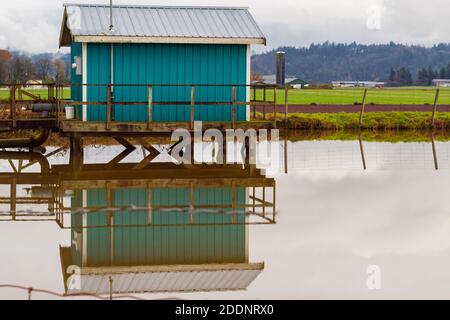 Blick auf das grüne Bootshaus auf dem Wasser mit Spiegelung. Reisefoto, Straßenansicht, selektiver Fokus. Stockfoto