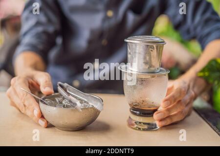 Kaukasischen Mann und traditionelle Tropfen gebrühten vietnamesischen Kaffee aus phinfilter Stockfoto
