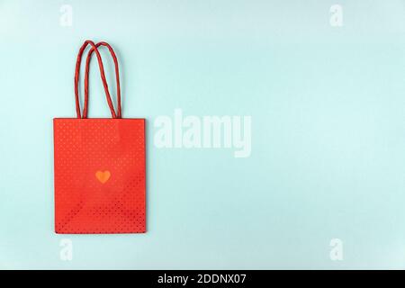 Valentinstag kreatives Konzept. Rote Papiertüte mit Herz auf blauem Hintergrund. Draufsicht, flach liegend, Platz für Text kopieren. Feiertagsfeier verführen. Stockfoto