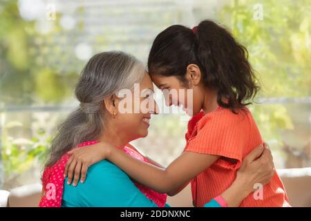 Enkelin und Enkelin berühren die Stirn und zeigen Zuneigung Ein Wohnzimmer Stockfoto