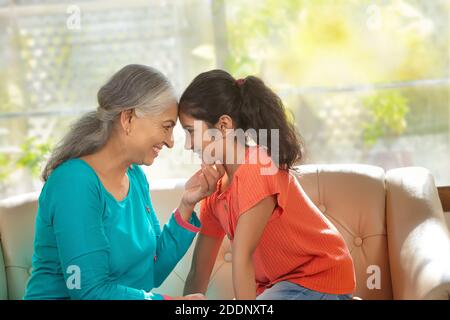 Enkelin und Enkelin berühren die Stirn und zeigen Zuneigung Ein Wohnzimmer Stockfoto
