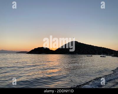 Wunderschöner Meerblick bei Sonnenuntergang, farbenfroh bei Sonnenaufgang. Spiegelungen auf dem Meer, Sonnenschirmen, Lichtern und Inseln auf der ägäis. Stockfoto