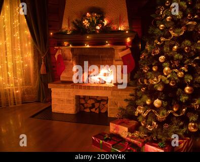 Weihnachtlich geschmückter Baum im dunklen Innenraum mit Kamin und Fenster Stockfoto