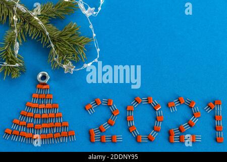 Kreative Weihnachtskarte. Zahlen 2021 und ein Weihnachtsbaum aus Transistoren auf blauem Hintergrund. Kreatives Konzept des neuen Jahres. Speicherplatz kopieren. Stockfoto