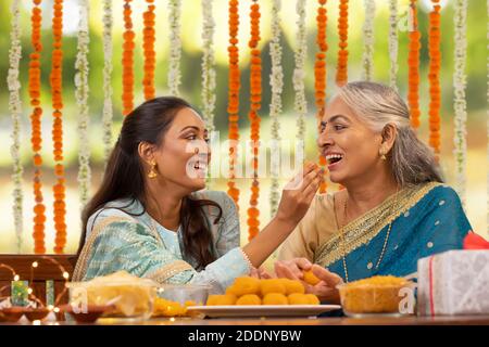 Schwiegertochter ernährt Schwiegermutter Laddoo während Diwali Feiern Stockfoto