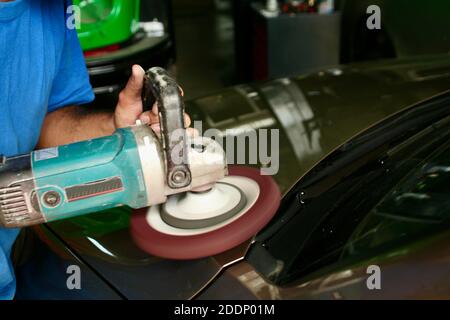 Mann Polieren Fronthaube des Autos durch Schleifmaschine. Auto Farbe und Detaillierung in der Service-Garage von Handwerker. Stockfoto