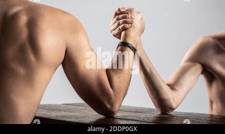 Zwei Männerhände umklammten Arm Wrestling, stark und schwach, ungleiche Übereinstimmung. Armdrücken. Schwer muskulös Mann Arm Wrestling ein mickrigen schwachen Mann. Arme Stockfoto