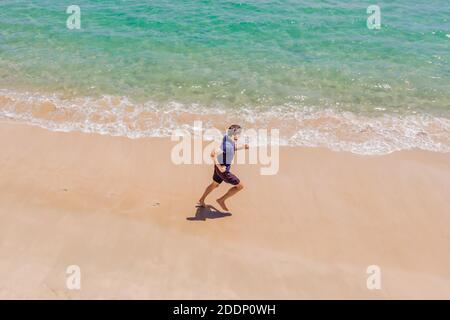 Läufer am Strand am Meer - Blick von oben. Mann Athlet Training Cardio Jogging tun Morgen Training. Hero Luftdrohne Ansicht erschossen, viele Stockfoto