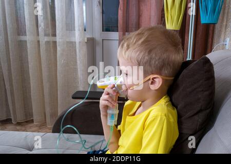 Ein 5-7-jähriger Junge in einem T-Shirt nimmt eine Inhalation zu Hause Stockfoto