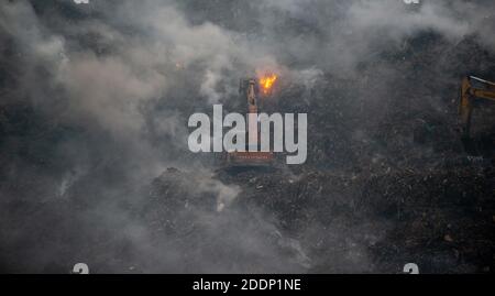 Neu Delhi, Indien. November 2020. Ein Bagger sah, wie er versuchte, den Schwelbrand auf einer Deponie zu löschen.von der Deponie Ghazipur stieg dichter Rauch auf, nachdem am frühen Morgen ein Feuer an einem Abfallberg ausbrach. Es ist ein doppelter Whammy zu Delhis bereits verschlechternder Verschmutzung. Die Luftqualität in Delhi verschlechtert sich und zeigt keine Anzeichen einer Verbesserung. Nach dem System der Luftqualität Wetterprognosen und Forschung, AQI stand bei 347 in der Kategorie "sehr schlecht". Kredit: SOPA Images Limited/Alamy Live Nachrichten Stockfoto