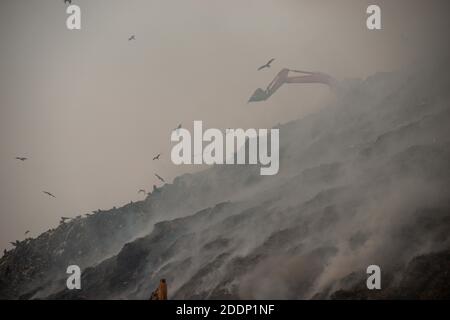 Neu Delhi, Indien. November 2020. Ein Bagger sah, wie er versuchte, den Schwelbrand auf einer Deponie zu löschen.von der Deponie Ghazipur stieg dichter Rauch auf, nachdem am frühen Morgen ein Feuer an einem Abfallberg ausbrach. Es ist ein doppelter Whammy zu Delhis bereits verschlechternder Verschmutzung. Die Luftqualität in Delhi verschlechtert sich und zeigt keine Anzeichen einer Verbesserung. Nach dem System der Luftqualität Wetterprognosen und Forschung, AQI stand bei 347 in der Kategorie "sehr schlecht". Kredit: SOPA Images Limited/Alamy Live Nachrichten Stockfoto