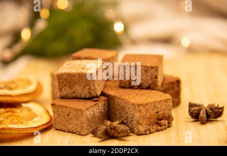 Duftende Gewürze und Marshmallows auf einem Holztablett, verziert mit Tannenzweigen und einer festlichen Girlande. Stockfoto