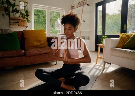 Junge afrikanerin, die in Lotusposition mit verbundenen Händen sitzt Auf Yoga-Matte üben Atemübungen Stockfoto