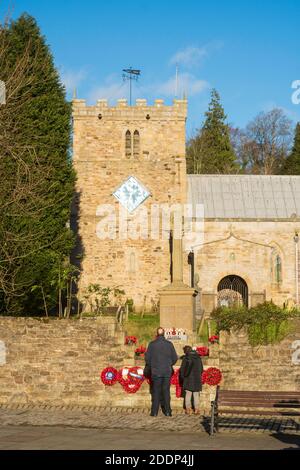 Älteres Paar inspiziert das Kriegsdenkmal und die Kirche des heiligen Apostels Thomas in Stanhope, Co. Durham, England, UK Stockfoto