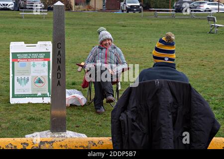 (201126) -- SURREY, 26. November 2020 (Xinhua) -- während des Thanksgiving-Feiertags am 25. November 2020 treffen sich Menschen im Peace Arch Historical State Park, wo ein kleiner Teil davon entlang der Kanada-US-Grenze abgegrenzt ist. Die Grenze zwischen den USA und Kanada ist seit März wegen COVID-19 für nicht-wesentlichen Verkehr gesperrt. Kanadische und amerikanische Freunde und Verwandte treffen sich während der amerikanischen Thanksgiving-Woche entlang der Grenze, obwohl sie durch die Grenzschließung getrennt sind. Der Peace Arch Historical State Park erstreckt sich über die Grenze und ermöglicht es Menschen beider Nationalitäten, sich während der Pandemie bo zu treffen Stockfoto