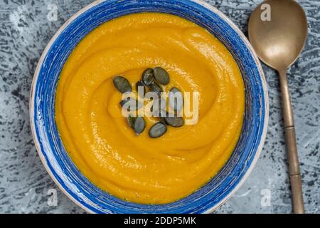 Geröstete Kürbis- und Karottensuppe mit Sahne und Kürbiskernen im Hintergrund. Nahaufnahme Stockfoto