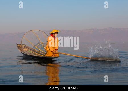 Inle Lake Myanmar Intha Leg Ruderfischer am Inle Lake, Myanmar (Burma), Asien im Februar - Fischer sitzen auf dem Boot plantschen, um Fische anzuziehen Stockfoto