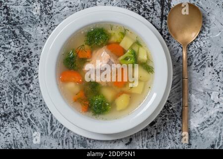 Frische Lachsfischsuppe mit Karotten, Kartoffeln und Zwiebeln auf einem weißen Teller, Nahaufnahme. Leckeres Abendessen besteht aus einer Fischsuppe mit Lachs. Draufsicht Stockfoto