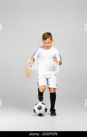 Kleiner Junge spielt mit Fußball über Studio Hintergrund. Stockfoto