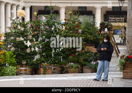 London, Großbritannien. November 2020. Eine Frau mit Gesichtsmaske als Vorsichtsmaßnahme gegen die Ausbreitung von covid 19, geht an den Weihnachtsbäumen in Covent Garden vorbei.zahlreiche Dekorationen wurden in der ganzen Stadt enthüllt, während die Hauptstadt sich auf die Feiertage vorbereitet. Kredit: SOPA Images Limited/Alamy Live Nachrichten Stockfoto