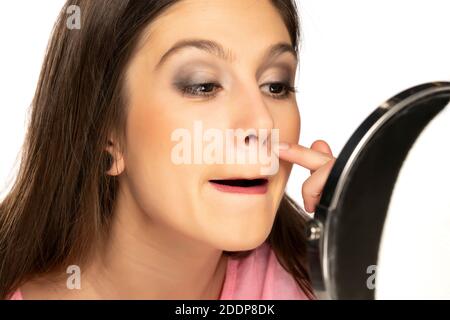 Eine junge Frau prüft ihr Gesicht vor einem Spiegel Stockfoto
