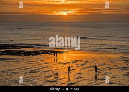 Swansea, Großbritannien. November 2020. Leute gehen am Strand spazieren, während die Sonne über Langland Bay in der Nähe von Swansea an einem kalten und frostigen Herbstmorgen aufgeht. Quelle: Phil Rees/Alamy Live News Stockfoto