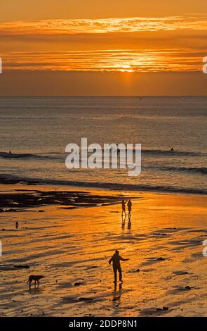Swansea, Großbritannien. November 2020. Leute gehen am Strand spazieren, während die Sonne über Langland Bay in der Nähe von Swansea an einem kalten und frostigen Herbstmorgen aufgeht. Quelle: Phil Rees/Alamy Live News Stockfoto