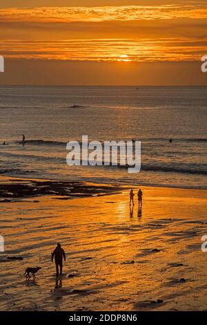 Swansea, Großbritannien. November 2020. Leute gehen am Strand spazieren, während die Sonne über Langland Bay in der Nähe von Swansea an einem kalten und frostigen Herbstmorgen aufgeht. Quelle: Phil Rees/Alamy Live News Stockfoto