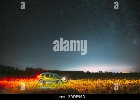 Milchstraße Galaxie in der Nacht Sternenhimmel mit leuchtenden Sternen über Green Car SUV in Landschaft. Milchstraße Galaxie Und Ländliche Feldwiese Stockfoto