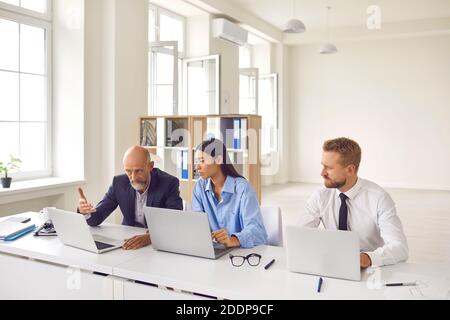 Seriöse, reife Betriebsleiterin und junge Auszubildende, die daran arbeiten Notebooks zusammen Stockfoto