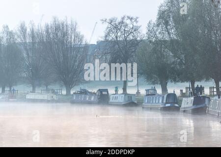 Cambridge, Großbritannien. November 2020. Nebel und Rauch steigen von Hausbooten, die an einem frostigen späten Herbstmorgen auf dem Fluss Cam festmachen. Die Temperaturen fielen über Nacht auf fast den Gefrierpunkt und in den nächsten Tagen wird mehr kaltes Wetter prognostiziert. Kredit: Julian Eales/Alamy Live Nachrichten Stockfoto