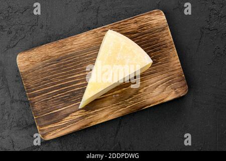 Draufsicht auf dreieckiges Stück Ziegenkäse auf Holzschneidebrett Stockfoto