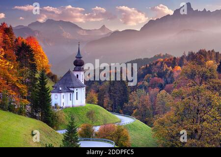 Bayerische Alpen. Landschaftsbild der Bayerischen Alpen mit Maria-Gern-Kirche und Watzmann-Berg bei schönem Herbstuntergang. Stockfoto