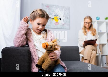 Unglücklich kleines Mädchen mit Spielzeug Besuch Psychologe Stockfoto