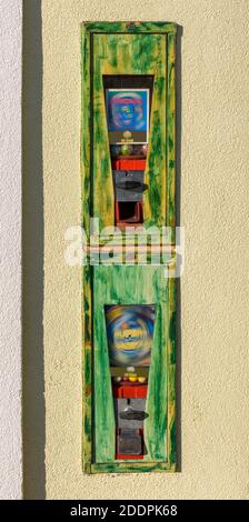 Zwei Gummiballmaschinen in alten Metallkisten in einem Wand Stockfoto