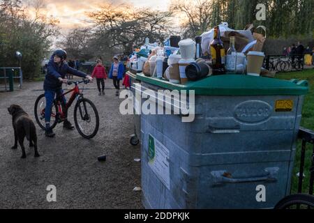 Hund und Kinder hängen in Hampstead Heath neben einem Mülltonne Überlauf mit Kaffeetassen und Alkoholflaschen, London, UK - 22. November 2020 Stockfoto