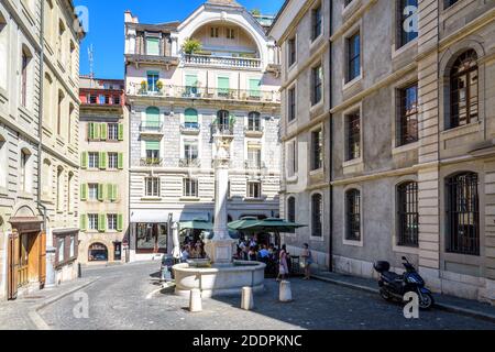 Der Brunnen am Place du Grand-Mezel in der Altstadt von Genf mit einem Straßencafé und einem typischen Wohngebäude im Heimatstil. Stockfoto