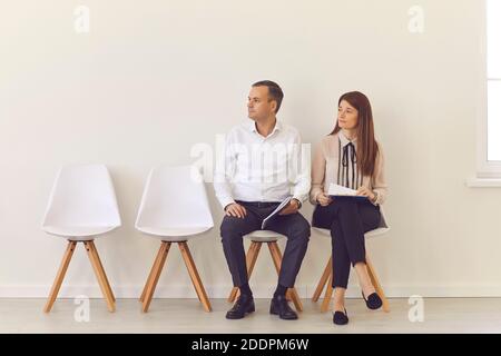 Selbstbewusste junge Kandidaten sitzen auf Stühlen in der Halle Warten auf ihr Interview Stockfoto