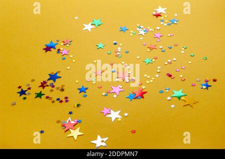 Bunte Sterne Konfetti auf gelbem Hintergrund. Karneval, Party-Dekor. Weihnachtsdekoration. Stockfoto