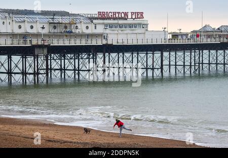 Brighton UK 26. November 2020 - EINE Frau unsere mit ihrem Hund von Brighton Palace Pier als die Stadt wechselt zu Tier 2 COVID Einschränkungen zusammen mit dem größten Teil von England, wie der Gesundheitsminister Matt Hancock hat die Tier Änderungen in England angekündigt, um zu helfen, gegen das Coronavirus COVID-19 Pandemie. Die neuen Stufen werden in Kraft treten am kommenden Mittwoch, wenn England kommt aus der jüngsten Lockdown-Einschränkungen : Credit Simon Dack / Alamy Live News Stockfoto