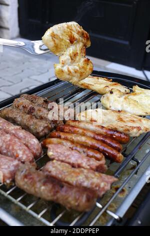 Grillen von Essen, Fleisch, Huhn im Hinterhof oder einer Terrasse auf einem kleinen billigen elektrischen Grill zu Hause.Huhn Fleisch auf einem bbq Gabel.Nahaufnahme. Stockfoto