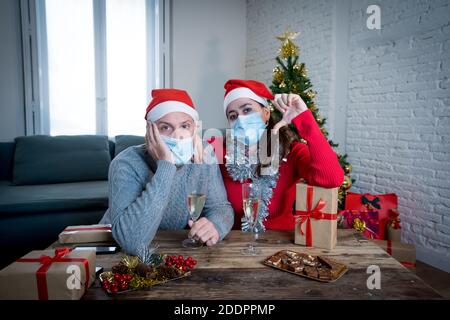 Trauriges Paar mit Maske in Selbstisolation auf Videoanruf mit Familie vermisst Weihnachten und Neujahr von Angesicht zu Angesicht feiern. Virtuelle Feiern und COV Stockfoto