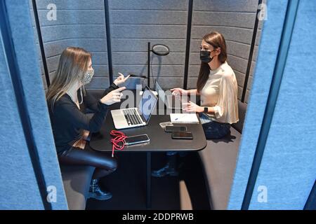 Themenbild Coworking Space: Zwei junge Frauen arbeiten am 22. November 2020 in einem Coworking-Büro an ihren Laptops. Coworking ist eine Entwicklung im Bereich der "neuen Arbeitsformen". Freiberufler, kleinere Startups oder digitale Nomaden arbeiten in meist größeren, relativ offenen Räumen und können so voneinander profitieren. Sie arbeiten entweder selbstständig in verschiedenen Unternehmen und Projekten oder entwickeln gemeinsam mit anderen Mitarbeitern Projekte. MODELL FREIGEGEBEN! Weltweite Nutzung Stockfoto