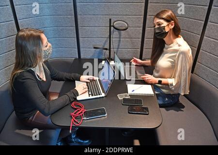 Themenbild Coworking Space: Zwei junge Frauen arbeiten am 22. November 2020 in einem Coworking-Büro an ihren Laptops. Coworking ist eine Entwicklung im Bereich der "neuen Arbeitsformen". Freiberufler, kleinere Startups oder digitale Nomaden arbeiten in meist größeren, relativ offenen Räumen und können so voneinander profitieren. Sie arbeiten entweder selbstständig in verschiedenen Unternehmen und Projekten oder entwickeln gemeinsam mit anderen Mitarbeitern Projekte. MODELL FREIGEGEBEN! Weltweite Nutzung Stockfoto