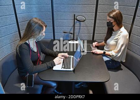 Themenbild Coworking Space: Zwei junge Frauen arbeiten am 22. November 2020 in einem Coworking-Büro an ihren Laptops. Coworking ist eine Entwicklung im Bereich der "neuen Arbeitsformen". Freiberufler, kleinere Startups oder digitale Nomaden arbeiten in meist größeren, relativ offenen Räumen und können so voneinander profitieren. Sie arbeiten entweder selbstständig in verschiedenen Unternehmen und Projekten oder entwickeln gemeinsam mit anderen Mitarbeitern Projekte. MODELL FREIGEGEBEN! Weltweite Nutzung Stockfoto